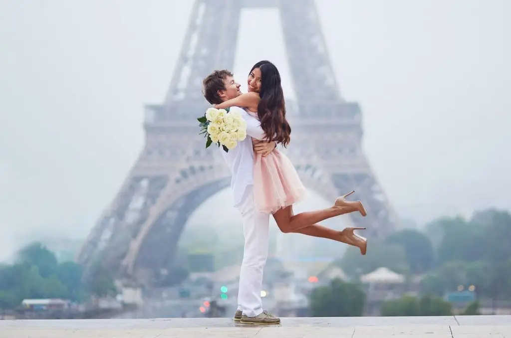 Couple smiling and hugging in front of the Eiffel Tower