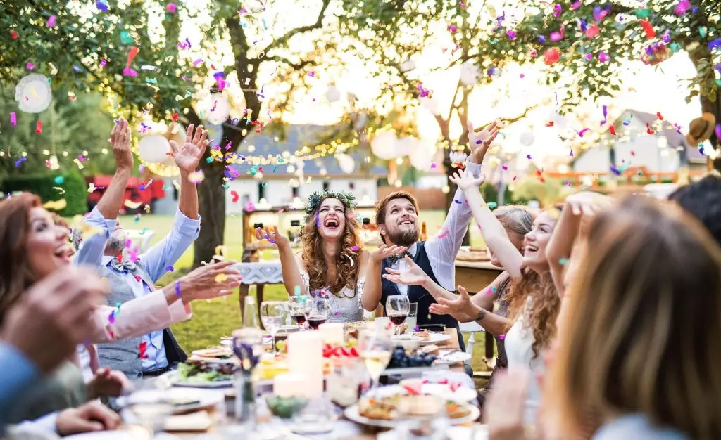 People at a wedding party cheer and throw confetti into the air