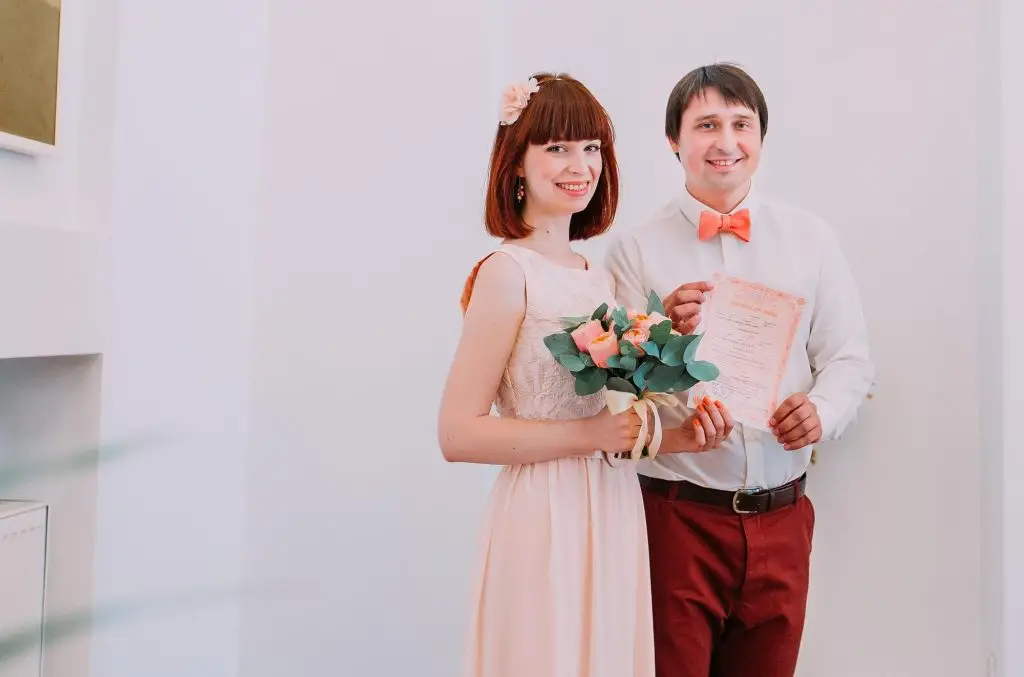 Couple smiling and holding marriage documentation