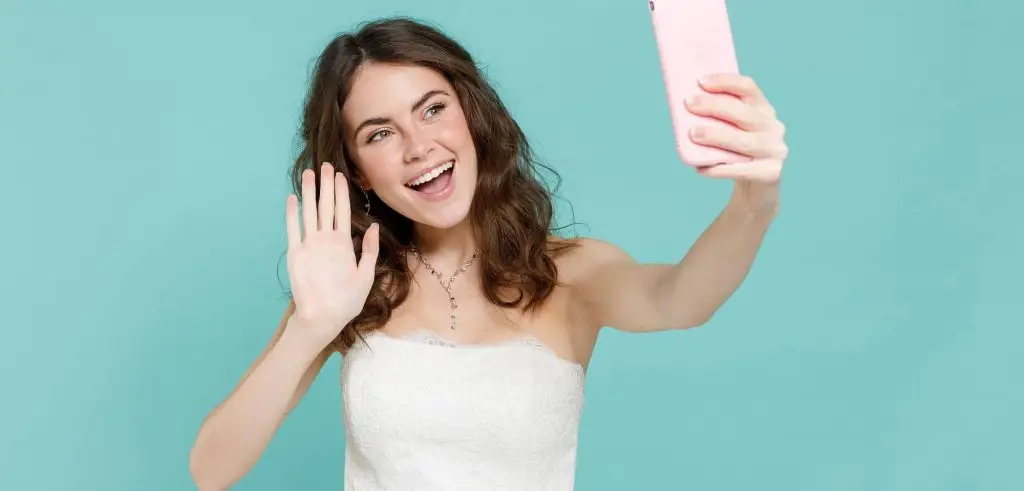 Woman smiles and waves to her partner over video call