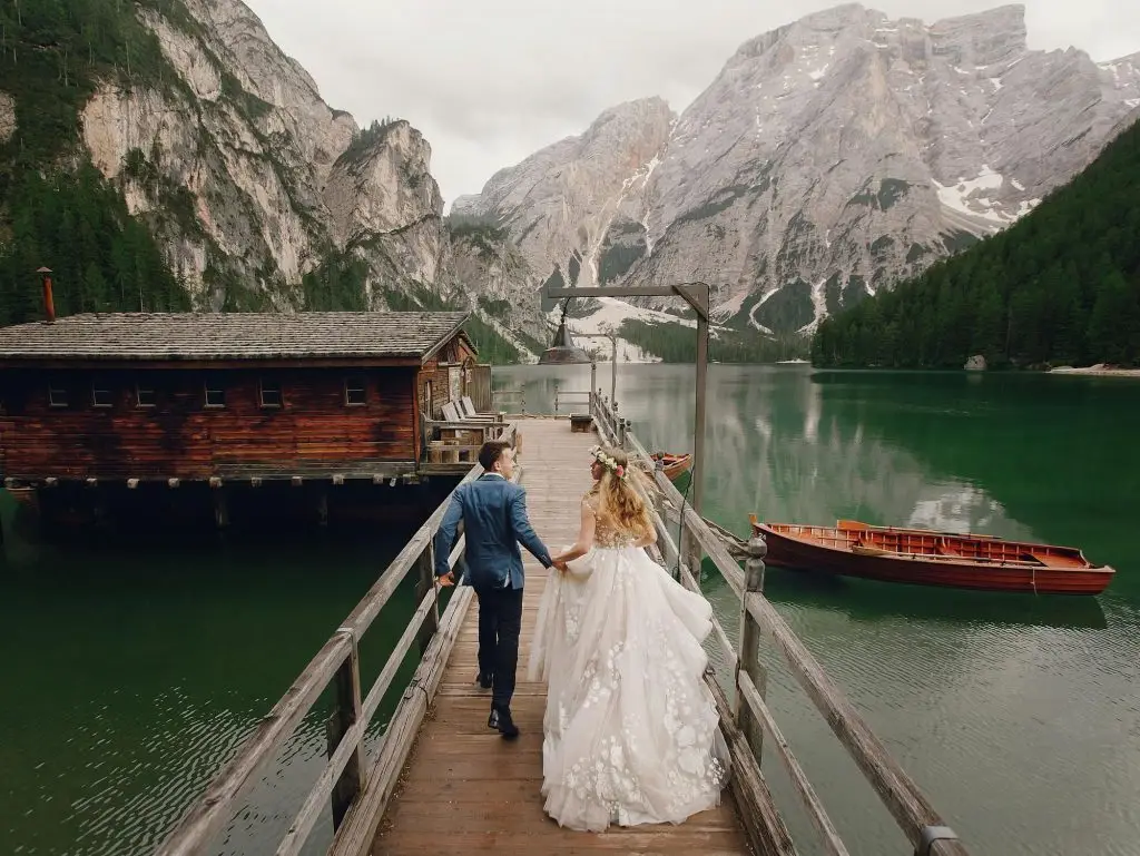 Married couple walking on a dock in the romantic mountain lake after getting married